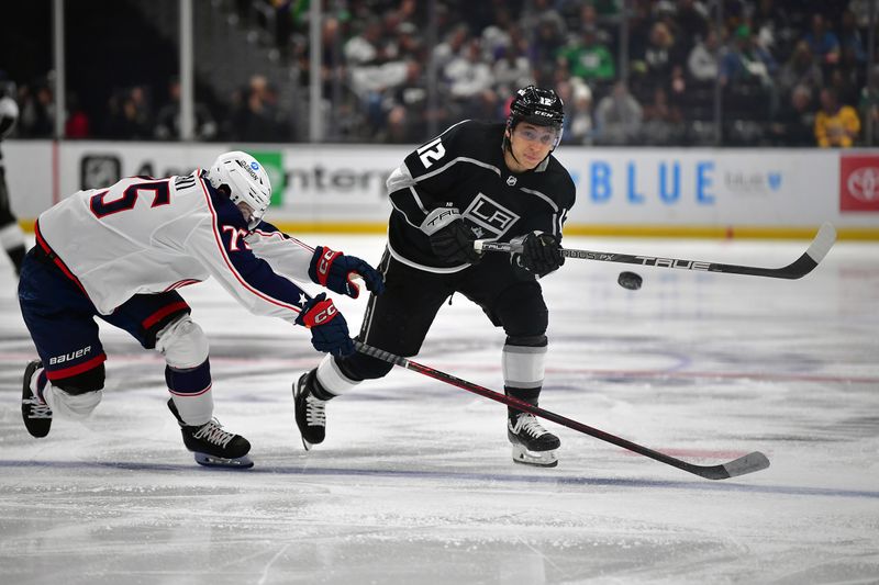 Mar 16, 2023; Los Angeles, California, USA; Los Angeles Kings left wing Trevor Moore (12) clears the puck against Columbus Blue Jackets defenseman Tim Berni (75) during the second period at Crypto.com Arena. Mandatory Credit: Gary A. Vasquez-USA TODAY Sports