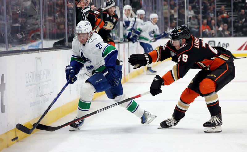 Mar 3, 2024; Anaheim, California, USA; Vancouver Canucks left wing Nils Hoglander (21) and Anaheim Ducks defenseman Gustav Lindstrom (28) battle for the puck during the first period at Honda Center. Mandatory Credit: Jason Parkhurst-USA TODAY Sports