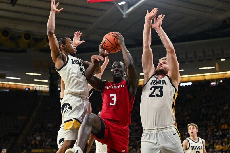 Jan 6, 2024; Iowa City, Iowa, USA; Rutgers Scarlet Knights forward Mawot Mag (3) goes to the basket as Iowa Hawkeyes forward Ben Krikke (23) and guard Dasonte Bowen (5) defend during the first half at Carver-Hawkeye Arena. Mandatory Credit: Jeffrey Becker-USA TODAY Sports