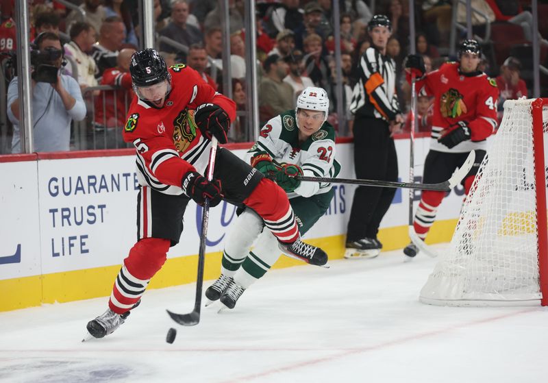 Oct 3, 2025; Chicago, Illinois, USA; Chicago Blackhawks defenseman Connor Murphy (5) clears the puck past Minnesota Wild forward Danila Yurov (22) during the second period at United Center. Mandatory Credit: Talia Sprague-Imagn Images