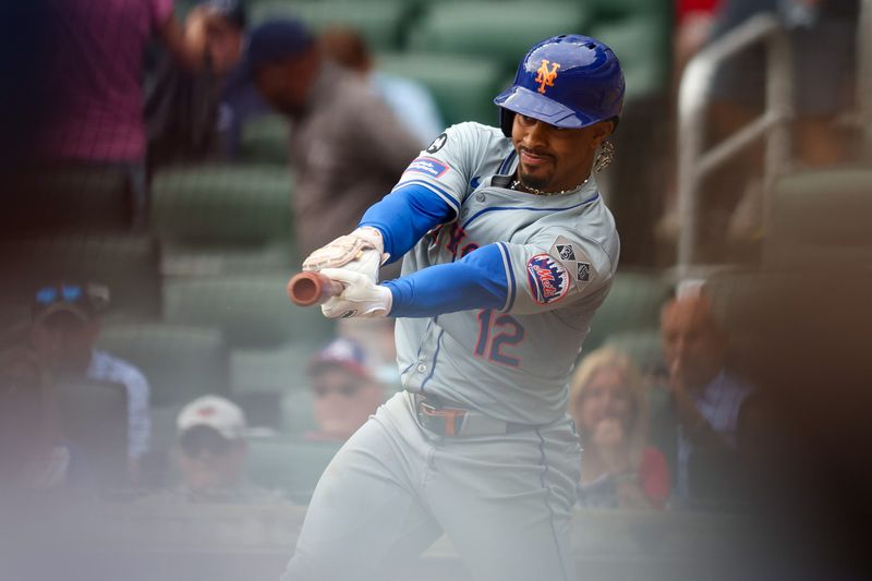Sep 30, 2024; Atlanta, Georgia, USA; New York Mets shortstop Francisco Lindor (12) hits a RBI single against the Atlanta Braves in the eighth inning at Truist Park. Mandatory Credit: Brett Davis-Imagn Images
