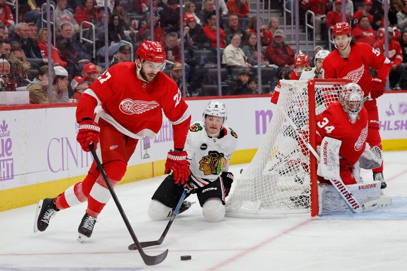 Nov 30, 2023; Detroit, Michigan, USA; Detroit Red Wings center Michael Rasmussen (27) skates with the puck chased by Chicago Blackhawks center Ryan Donato (8) in the third period at Little Caesars Arena. Mandatory Credit: Rick Osentoski-USA TODAY Sports