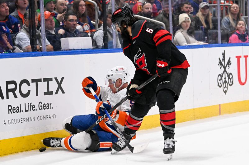 Mar 19, 2024; Elmont, New York, USA; New York Islanders center Casey Cizikas (53) plays the puck from the ice defended by Carolina Hurricanes defenseman Jalen Chatfield (5) during the second period at UBS Arena. Mandatory Credit: Dennis Schneidler-USA TODAY Sports