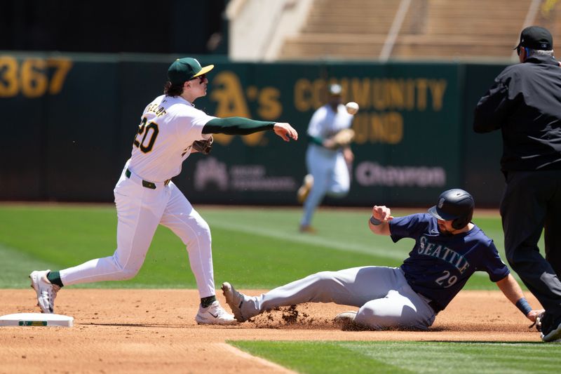 Jun 6, 2024; Oakland, California, USA; Oakland Athletics second baseman Zack Gelof (20) throws over Seattle Mariners catcher Cal Raleigh (29) to complete a double play during the second inning at Oakland-Alameda County Coliseum. Mandatory Credit: D. Ross Cameron-USA TODAY Sports