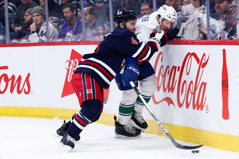 Jan 14, 2025; Winnipeg, Manitoba, CAN;  Winnipeg Jets defenseman Neal Pionk (4) boards Vancouver Canucks forward J.T. Miller (9) during the first period at Canada Life Centre. Mandatory Credit: Terrence Lee-Imagn Images