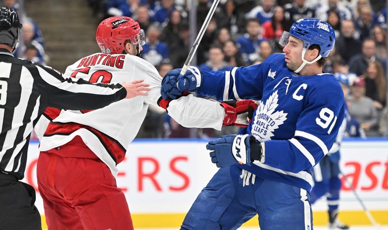 Dec 30, 2023; Toronto, Ontario, CAN; Carolina Hurricanes forward Michael Bunting (58) pushes Toronto Maple Leafs forward John Tavares (91) in the first period at Scotiabank Arena. Mandatory Credit: Dan Hamilton-USA TODAY Sports