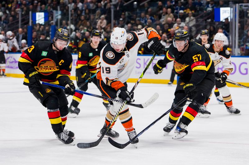 Nov 28, 2023; Vancouver, British Columbia, CAN; Vancouver Canucks defenseman Quinn Hughes (43) and defenseman Tyler Myers (57) stick check Anaheim Ducks forward Troy Terry (19) in the third period at Rogers Arena. Vancouver won 3-1. Mandatory Credit: Bob Frid-USA TODAY Sports