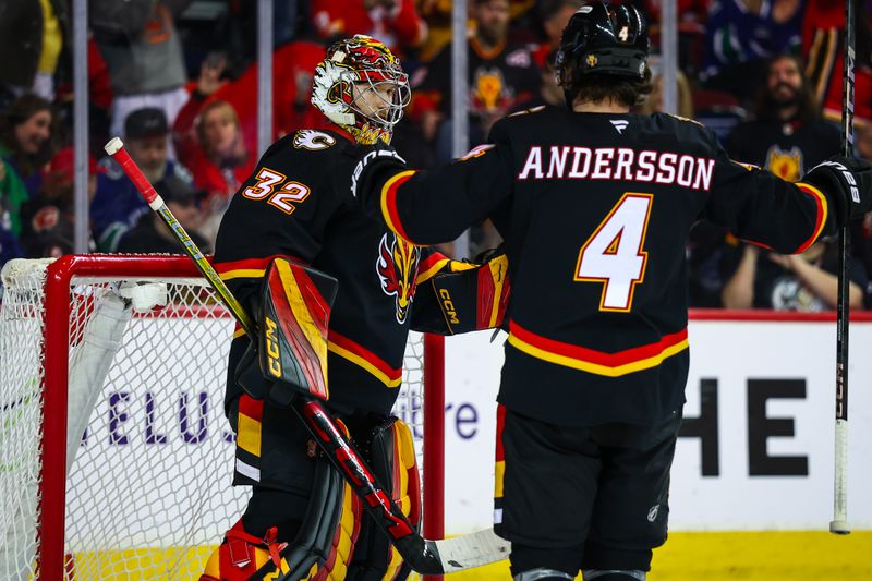 Dec 31, 2024; Calgary, Alberta, CAN; Calgary Flames goaltender Dustin Wolf (32) celebrates win with defenseman Rasmus Andersson (4) over Vancouver Canucks at Scotiabank Saddledome. Mandatory Credit: Sergei Belski-Imagn Images