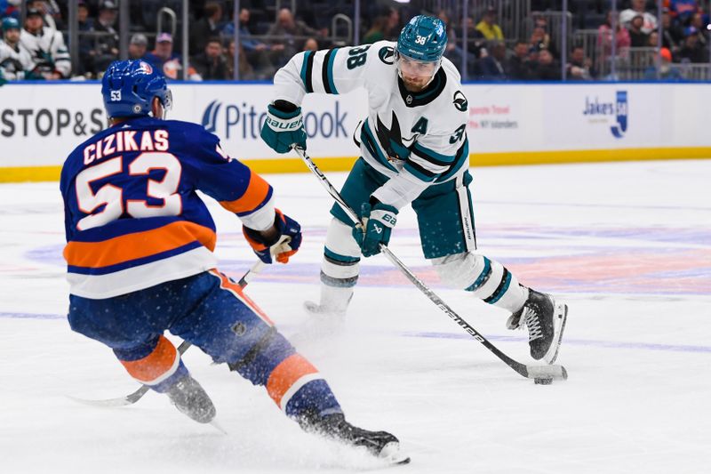 Dec 5, 2023; Elmont, New York, USA; San Jose Sharks defenseman Mario Ferraro (38) attempts a shot defended by New York Islanders center Casey Cizikas (53) during the third period at UBS Arena. Mandatory Credit: Dennis Schneidler-USA TODAY Sports