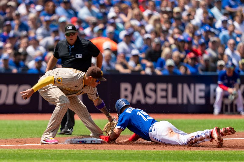 Jul 20, 2023; Toronto, Ontario, CAN; San Diego Padres third baseman Manny Machado (13) tags out Toronto Blue Jays second baseman Whit Merrifield (15) during the second inning at Rogers Centre. Mandatory Credit: Kevin Sousa-USA TODAY Sports