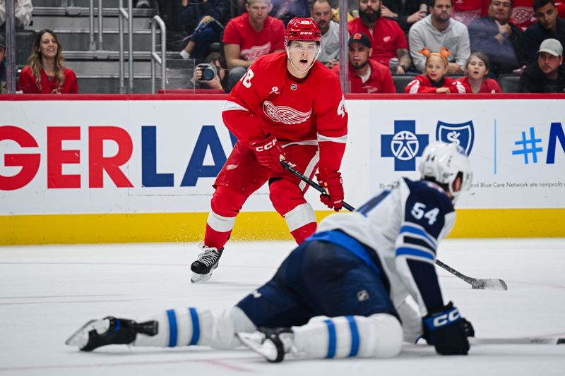 Oct 30, 2024; Detroit, Michigan, USA; Detroit Red Wings right wing Jonatan Berggren (48) looks to pass around Winnipeg Jets defenseman Dylan Samberg (54) during the game at Little Caesars Arena. Mandatory Credit: Tim Fuller-Imagn Images