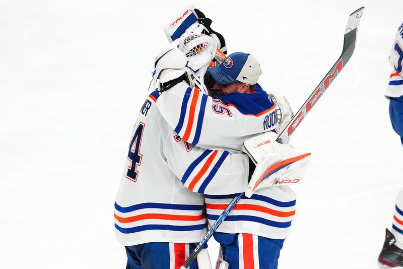 May 14, 2025; Las Vegas, Nevada, USA; Edmonton Oilers goaltender Stuart Skinner (74) celebrates with goaltender Olivier Rodrigue (35) after the Oilers defeated the Vegas Golden Knights 1-0 overtime victory and a 4-1 series win during game five of the second round of the 2025 Stanley Cup Playoffs at T-Mobile Arena. Mandatory Credit: Stephen R. Sylvanie-Imagn Images