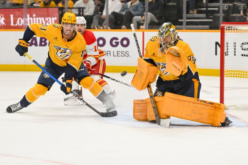 Dec 2, 2025; Nashville, Tennessee, USA;  Nashville Predators goaltender Juuse Saros (74) blocks the buck against the Calgary Flames during the second period at Bridgestone Arena. Mandatory Credit: Steve Roberts-Imagn Images