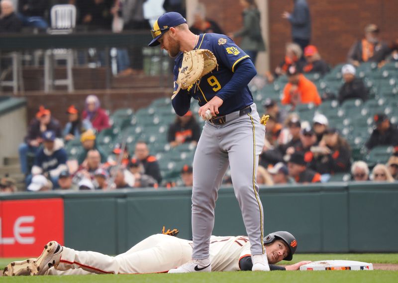 Apr 24, 2025; San Francisco, California, USA; San Francisco Giants right fielder Mike Yastrzemski (5) looks up after diving back to first base after Milwaukee Brewers first baseman Jake Bauers (9) during the first inning at Oracle Park. Mandatory Credit: Kelley L Cox-Imagn Images
