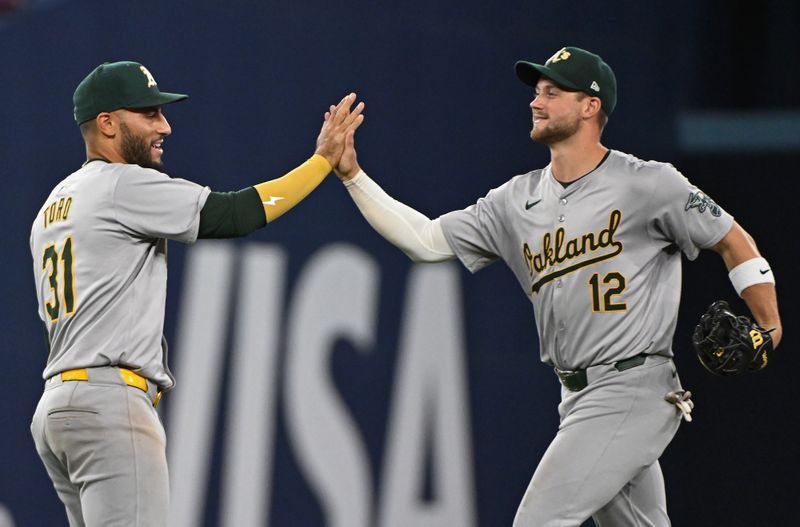 Aug 11, 2024; Toronto, Ontario, CAN; Oakland Athletics third base Abraham Toro (31) and Oakland Athletics short stop Max Schuemann (12) celebrate the win over the Toronto Blue Jays at Rogers Centre. Mandatory Credit: Gerry Angus-USA TODAY Sports