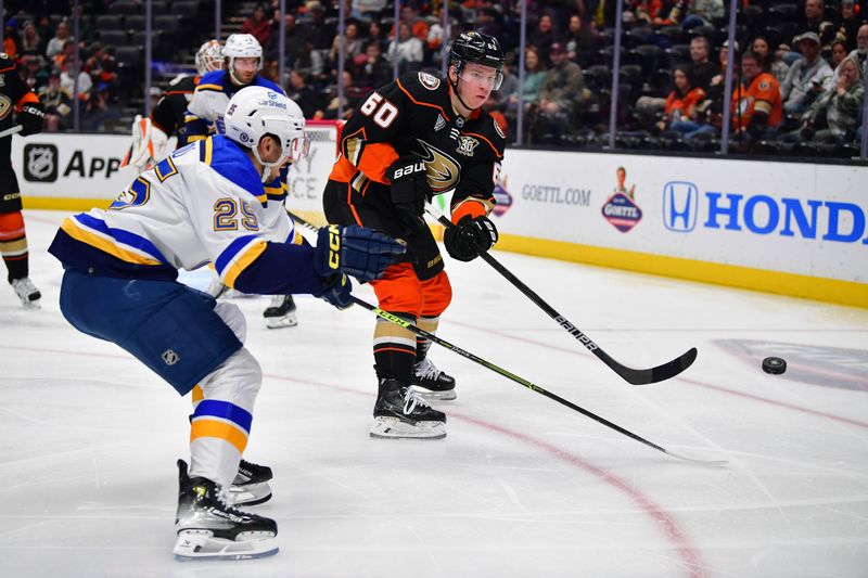 Apr 7, 2024; Anaheim, California, USA; Anaheim Ducks defenseman Jackson LaCombe (60) clears the puck against St. Louis Blues center Jordan Kyrou (25) during the first period at Honda Center. Mandatory Credit: Gary A. Vasquez-USA TODAY Sports