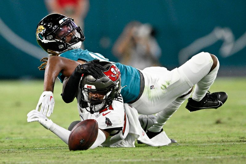 Jacksonville Jaguars wide receiver Joshua Cephus, top fumbles the ball after being hit by Tampa Bay Buccaneers cornerback Andrew Hayes, bottom, during the second half of an NFL preseason football game, Saturday, Aug. 17, 2024, in Jacksonville, Fla. (AP Photo/Phelan M. Ebenhack)