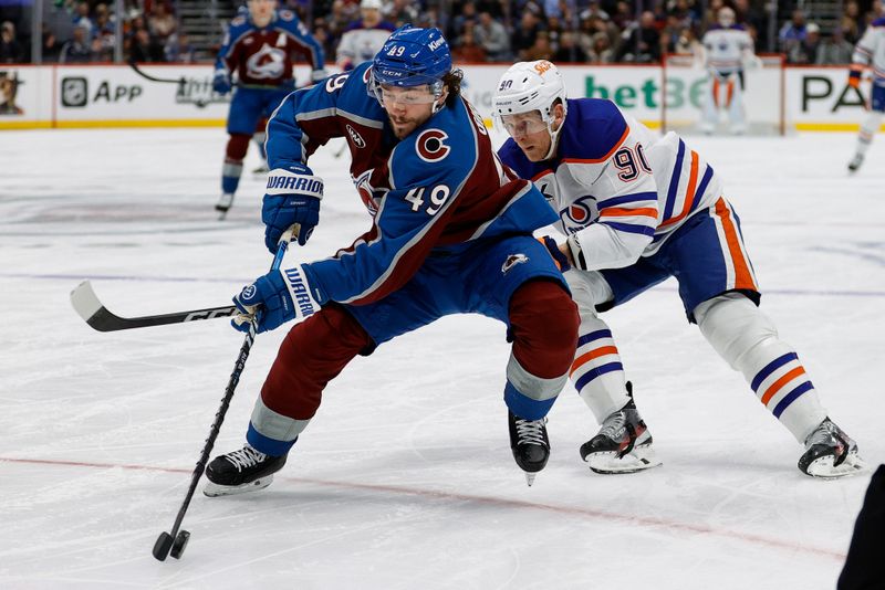 Jan 16, 2025; Denver, Colorado, USA; Colorado Avalanche defenseman Samuel Girard (49) controls the puck under pressure from Edmonton Oilers right wing Corey Perry (90) in the first period at Ball Arena. Mandatory Credit: Isaiah J. Downing-Imagn Images