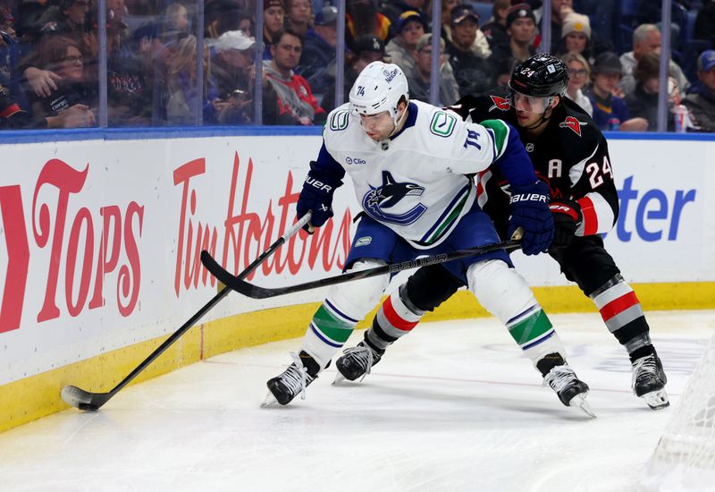 Nov 29, 2024; Buffalo, New York, USA;  Vancouver Canucks left wing Jake DeBrusk (74) controls the puck as Buffalo Sabres center Dylan Cozens (24) defends during the third period at KeyBank Center. Mandatory Credit: Timothy T. Ludwig-Imagn Images