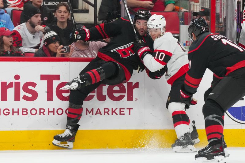 Feb 3, 2026; Raleigh, North Carolina, USA;  Ottawa Senators defenseman Jordan Spence (10) checks Carolina Hurricanes left wing Jordan Martinook (48) during the third period at Lenovo Center. Mandatory Credit: James Guillory-Imagn Images
