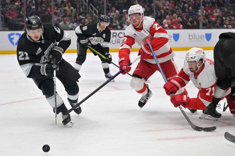 Nov 16, 2024; Los Angeles, California, USA; Los Angeles Kings defenseman Jordan Spence (21) controls the puck from Detroit Red Wings left wing Lucas Raymond (23) and center Dylan Larkin (71) in the third period at Crypto.com Arena. Mandatory Credit: Jayne Kamin-Oncea-Imagn Images