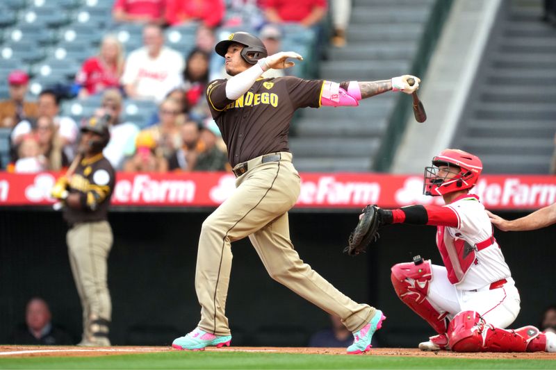 Jun 3, 2024; Anaheim, California, USA; San Diego Padres third baseman Manny Machado (13) hits a home run in the first inning as Los Angeles Angels catcher Logan O'Hoppe (14) watches at Angel Stadium. Mandatory Credit: Kirby Lee-USA TODAY Sports