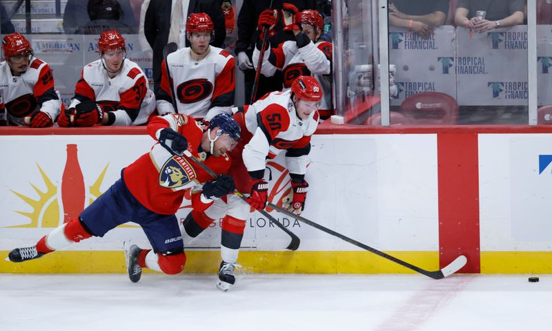 Dec 19, 2025; Sunrise, Florida, USA;  Florida Panthers center Sam Bennett (9) and Carolina Hurricanes left wing Eric Robinson (50) chase the puck during the third period at Amerant Bank Arena. Mandatory Credit: Rhona Wise-Imagn Images