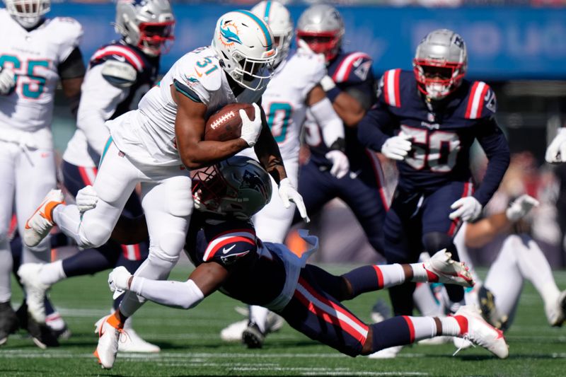 Miami Dolphins running back Raheem Mostert (31) tries to break free from a tackle during the first half of an NFL football game against the New England Patriots, Sunday, Oct. 6, 2024, in Foxborough, Mass. (AP Photo/Steven Senne)