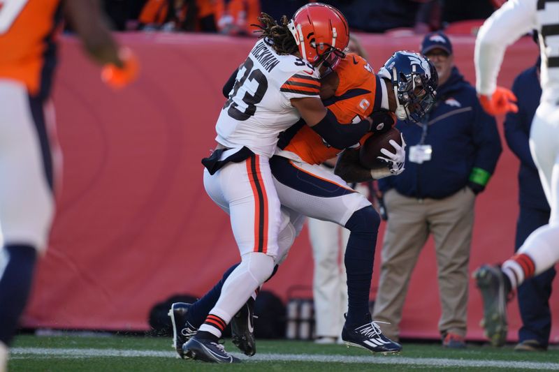 Cleveland Browns safety Ronnie Hickman (33) tackles Denver Broncos wide receiver Courtland Sutton (14) in the first half of an NFL football game Sunday, Nov. 26, 2023, in Denver. (AP Photo/David Zalubowski)