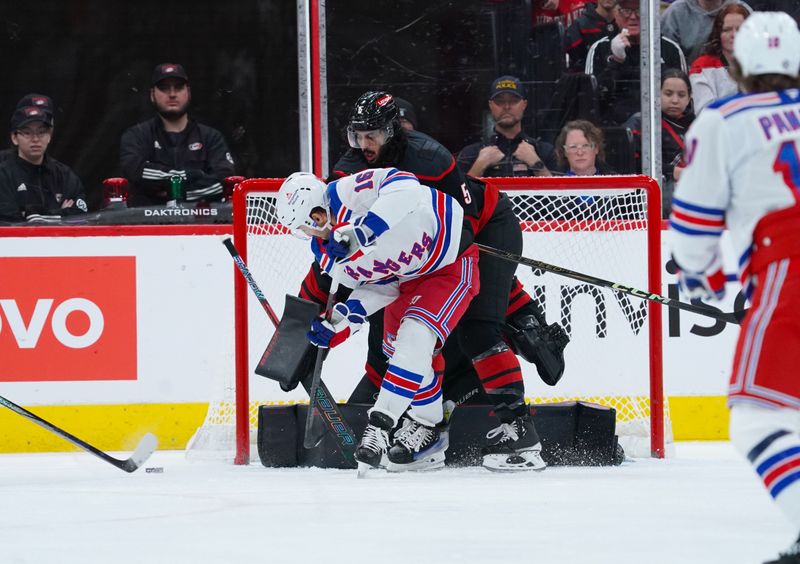 Nov 27, 2024; Raleigh, North Carolina, USA;  Carolina Hurricanes defenseman Jalen Chatfield (5) helps defend the net against New York Rangers center Vincent Trocheck (16) during the first period at Lenovo Center. Mandatory Credit: James Guillory-Imagn Images