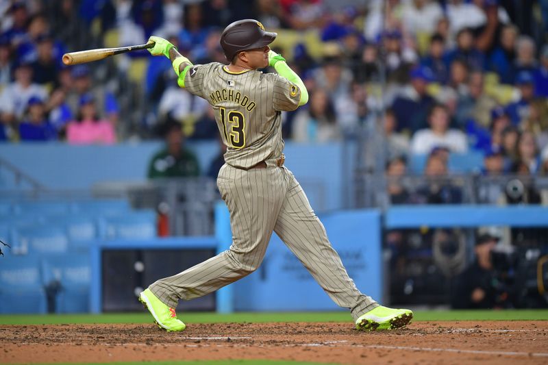 Sep 24, 2024; Los Angeles, California, USA; San Diego Padres third baseman Manny Machado (13) hits a double against the Los Angeles Dodgers during the eighth inning at Dodger Stadium. Mandatory Credit: Gary A. Vasquez-Imagn Images