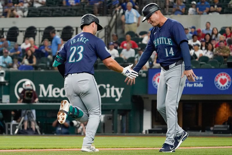 Apr 25, 2024; Arlington, Texas, USA; Seattle Mariners first baseman Ty France (23) slaps the hand of third base coach Manny Acta (14) after hitting a two run home run during the first inning against the Texas Rangers at Globe Life Field. Mandatory Credit: Raymond Carlin III-USA TODAY Sports