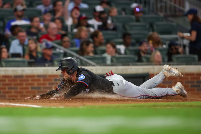 Aug 3, 2024; Atlanta, Georgia, USA; Miami Marlins catcher Nick Fortes (4) slides home safely to score a run against the Atlanta Braves in the fifth inning at Truist Park. Mandatory Credit: Brett Davis-USA TODAY Sports