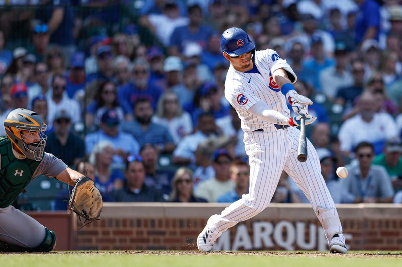 Sep 18, 2024; Chicago, Illinois, USA; Chicago Cubs outfielder Seiya Suzuki (27) hits an RBI-single against the Oakland Athletics during the fifth inning at Wrigley Field. Mandatory Credit: Kamil Krzaczynski-Imagn Images