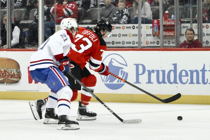 Feb 24, 2024; Newark, New Jersey, USA; New Jersey Devils right wing Tyler Toffoli (73) skates with the puck while being defended by Montreal Canadiens defenseman Kaiden Guhle (21) during the second period at Prudential Center. Mandatory Credit: John Jones-USA TODAY Sports