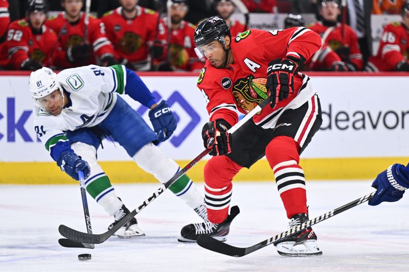 Feb 13, 2024; Chicago, Illinois, USA; Chicago Blackhawks defenseman Seth Jones (4) controls the puck while being defended by Vancouver Canucks forward Dakota Joshua (81) in the first period at United Center. Mandatory Credit: Jamie Sabau-USA TODAY Sports