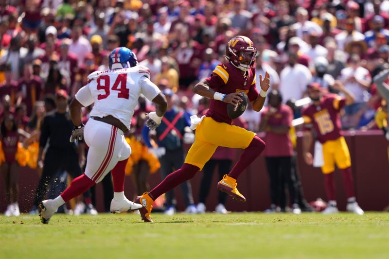 Washington Commanders quarterback Jayden Daniels, right, runs past New York Giants defensive tackle Elijah Chatman, left, for a first down during the first half of an NFL football game in Landover, Md., Sunday, Sept. 15, 2024. (AP Photo/Matt Slocum)