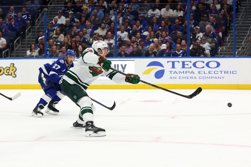 Oct 24, 2024; Tampa, Florida, USA; Minnesota Wild left wing Matt Boldy (12) shoots as Tampa Bay Lightning defenseman Ryan McDonagh (27) defends during the second period at Amalie Arena. Mandatory Credit: Kim Klement Neitzel-Imagn Images