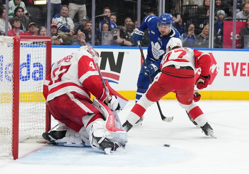 Apr 13, 2024; Toronto, Ontario, CAN; Toronto Maple Leafs center Auston Matthews (34) battles for the rebound in front of Detroit Red Wings defenseman Simon Edvinsson (77) and goaltender James Reimer (47) during the third period at Scotiabank Arena. Mandatory Credit: Nick Turchiaro-USA TODAY Sports