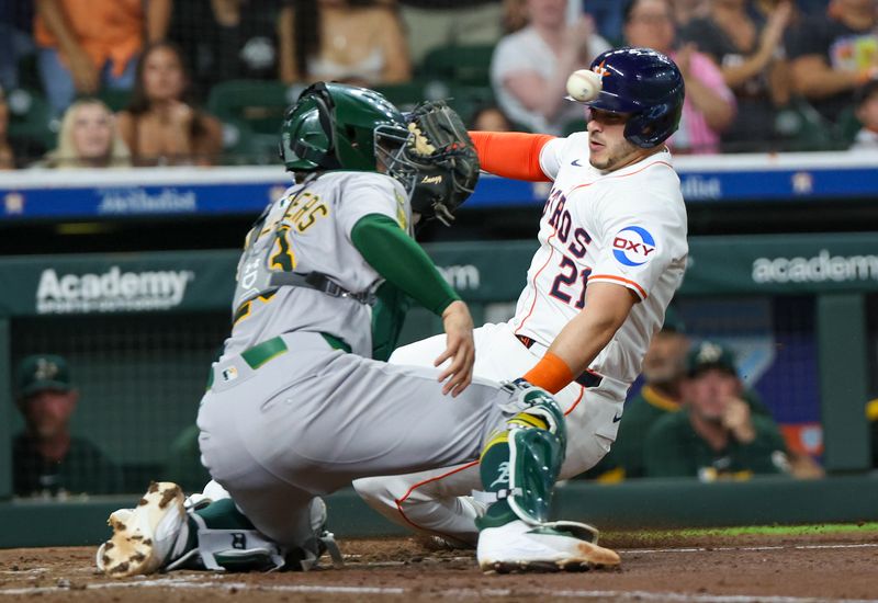 May 27, 2025; Houston, Texas, USA; Houston Astros catcher Yainer Diaz (21) slides safely at home against Athletics catcher Shea Langeliers (23) on  left fielder Chas McCormick (20) (not pictured) RBI double in the second inning at Daikin Park. Mandatory Credit: Thomas Shea-Imagn Images