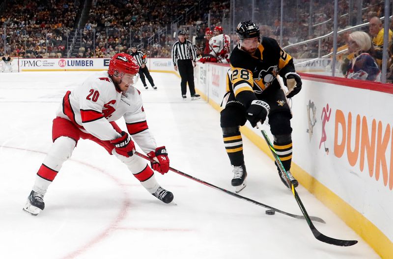 Oct 18, 2024; Pittsburgh, Pennsylvania, USA;  Carolina Hurricanes center Sebastian Aho (20) and Pittsburgh Penguins defenseman Marcus Pettersson (28) reach for a loose puck during the third period at PPG Paints Arena. Mandatory Credit: Charles LeClaire-Imagn Images