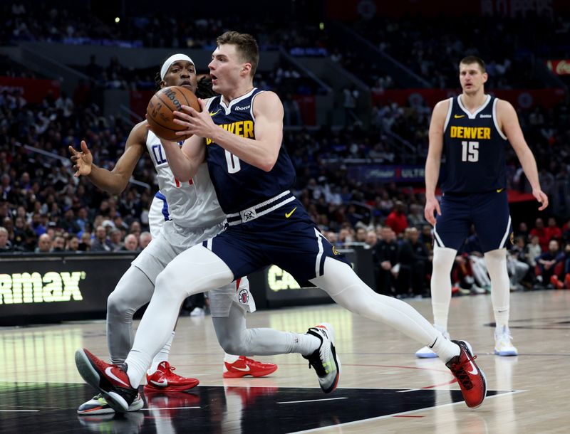 LOS ANGELES, CALIFORNIA - APRIL 04: Christian Braun #0 of the Denver Nuggets drives to the basket on Terance Mann #14 of the LA Clippers during a 102-100 Clippers win at Crypto.com Arena on April 04, 2024 in Los Angeles, California. User is consenting to the terms and conditions of the Getty Images License Agreement. (Photo by Harry How/Getty Images)