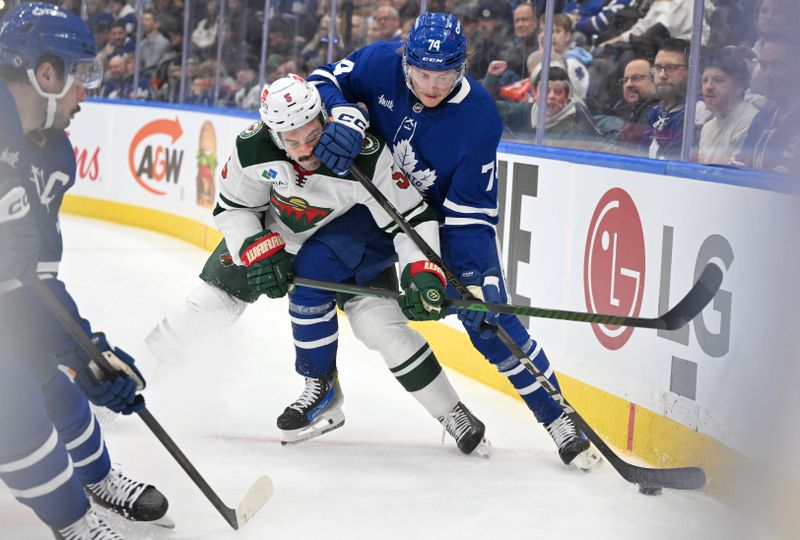 Jan 29, 2025; Toronto, Ontario, CAN;  Toronto Maple Leafs forward Bobby McMann (74) battles for the puck against Minnesota Wild defenseman Jake Middleton (5) in the first period at Scotiabank Arena. Mandatory Credit: Dan Hamilton-Imagn Images