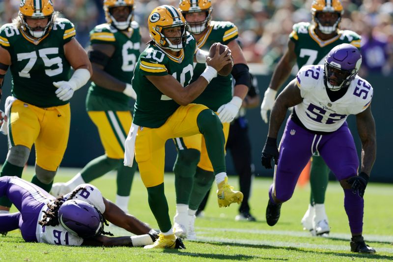 Green Bay Packers quarterback Jordan Love (10) runs the ball past Minnesota Vikings linebacker Pat Jones II (91) and linebacker Jihad Ward (52) during the first half of an NFL football game Sunday, Sept. 29, 2024, in Green Bay, Wis. (AP Photo/Matt Ludtke)