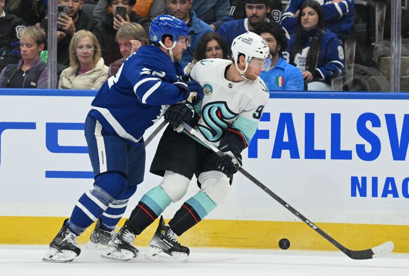 Oct 31, 2024; Toronto, Ontario, CAN;  Toronto Maple Leafs defenseman Jake McCabe body checks Seattle Kraken forward Andre Burakovsky (95) in the first period at Scotiabank Arena. Mandatory Credit: Dan Hamilton-Imagn Images