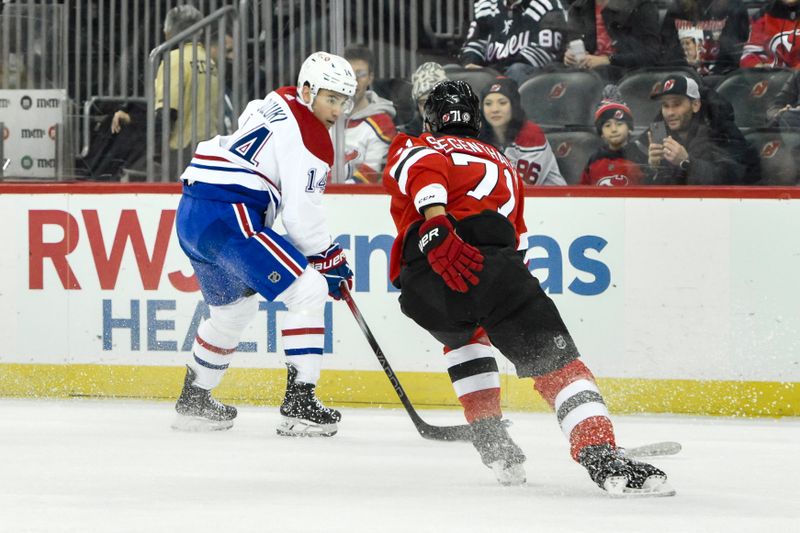 Feb 24, 2024; Newark, New Jersey, USA; Montreal Canadiens center Nick Suzuki (14) tries to get past New Jersey Devils defenseman Jonas Siegenthaler (71) during the first period at Prudential Center. Mandatory Credit: John Jones-USA TODAY Sports