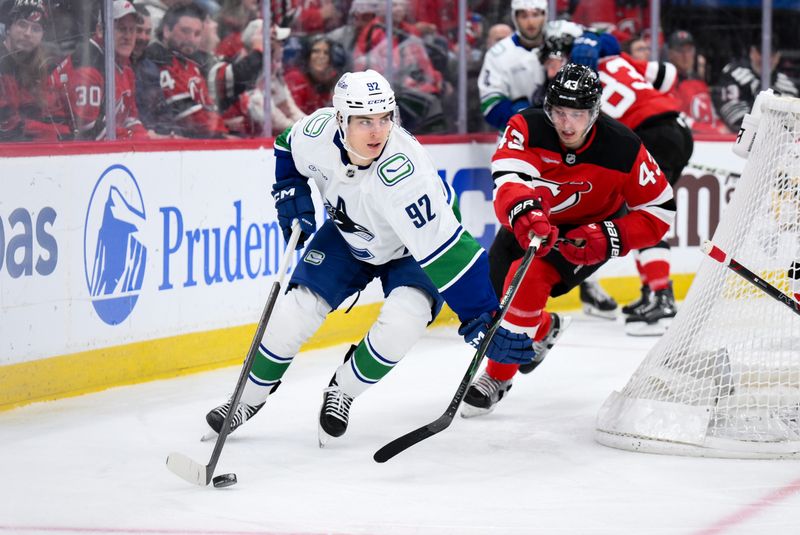 Dec 14, 2025; Newark, New Jersey, USA; Vancouver Canucks left wing Liam Ohgren (92) skates with the puck while defended by New Jersey Devils defenseman Luke Hughes (43) during the first period at Prudential Center. Mandatory Credit: John Jones-Imagn Images