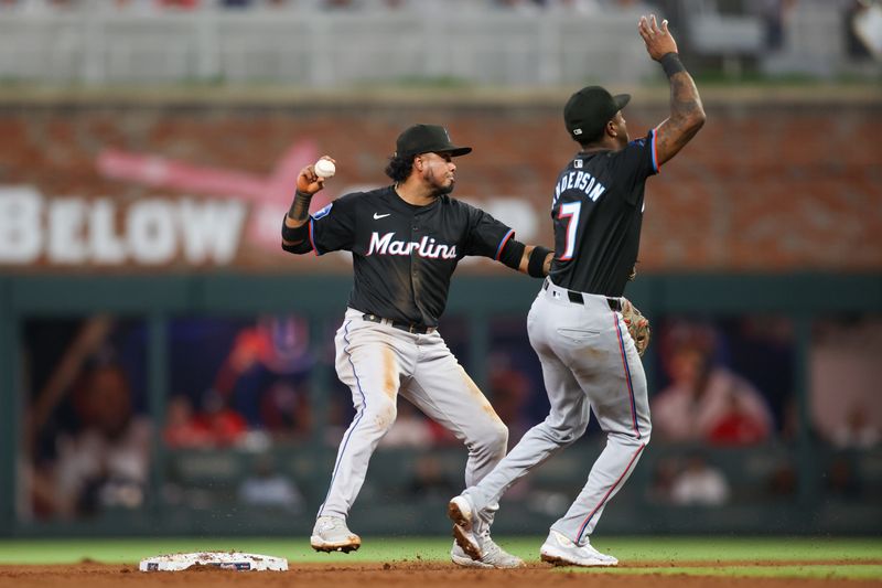 Apr 24, 2024; Atlanta, Georgia, USA; Miami Marlins second baseman Luis Arraez (3) turns a double play past shortstop Tim Anderson (7) against the Atlanta Braves in the fourth inning at Truist Park. Mandatory Credit: Brett Davis-USA TODAY Sports