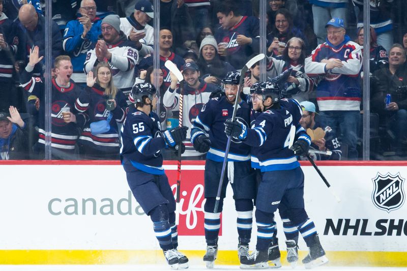 Jan 9, 2024; Winnipeg, Manitoba, CAN; Winnipeg Jets defenseman Brenden Dillon (5) is congratulated by his teammates on his goal against the Columbus Blue Jackets during the first period at Canada Life Centre. Mandatory Credit: Terrence Lee-USA TODAY Sports