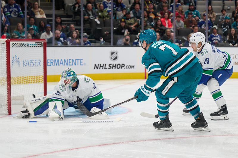 Nov 2, 2024; San Jose, California, USA; San Jose Sharks center Nico Sturm (7) scores a goal against Vancouver Canucks goaltender Kevin Lankinen (32) and defenseman Erik Brannstrom (26) during the second period at SAP Center at San Jose. Mandatory Credit: Robert Edwards-Imagn Images